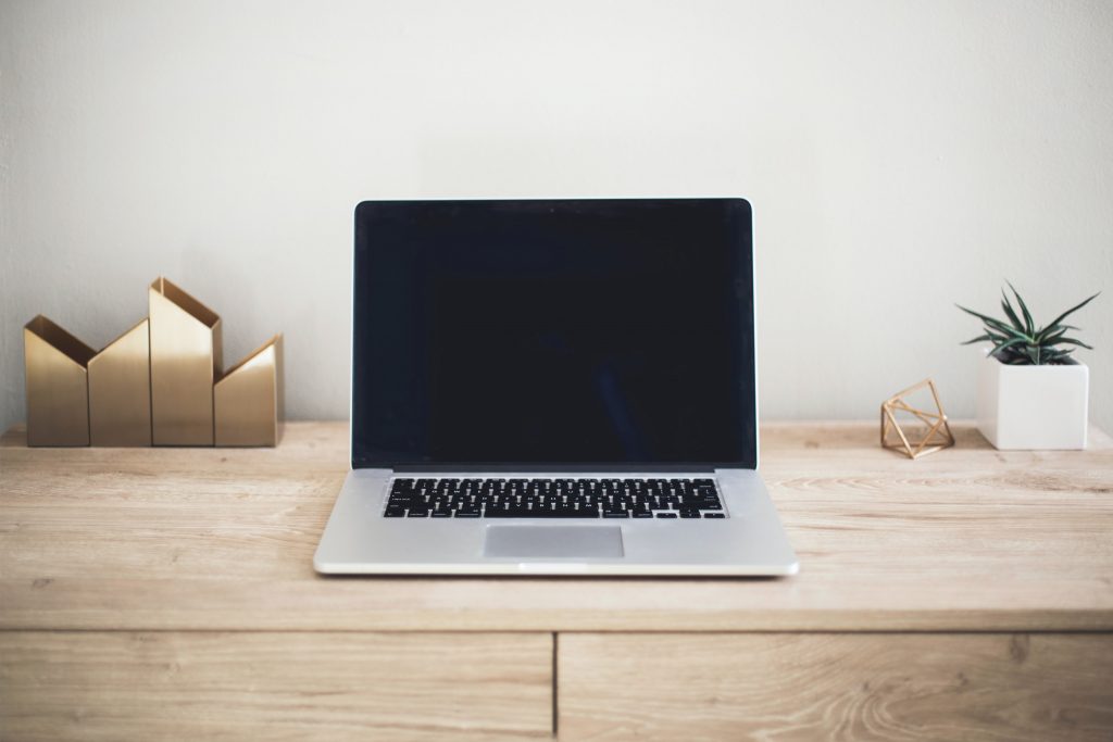 A silver Macbook pro on top of a wooden table